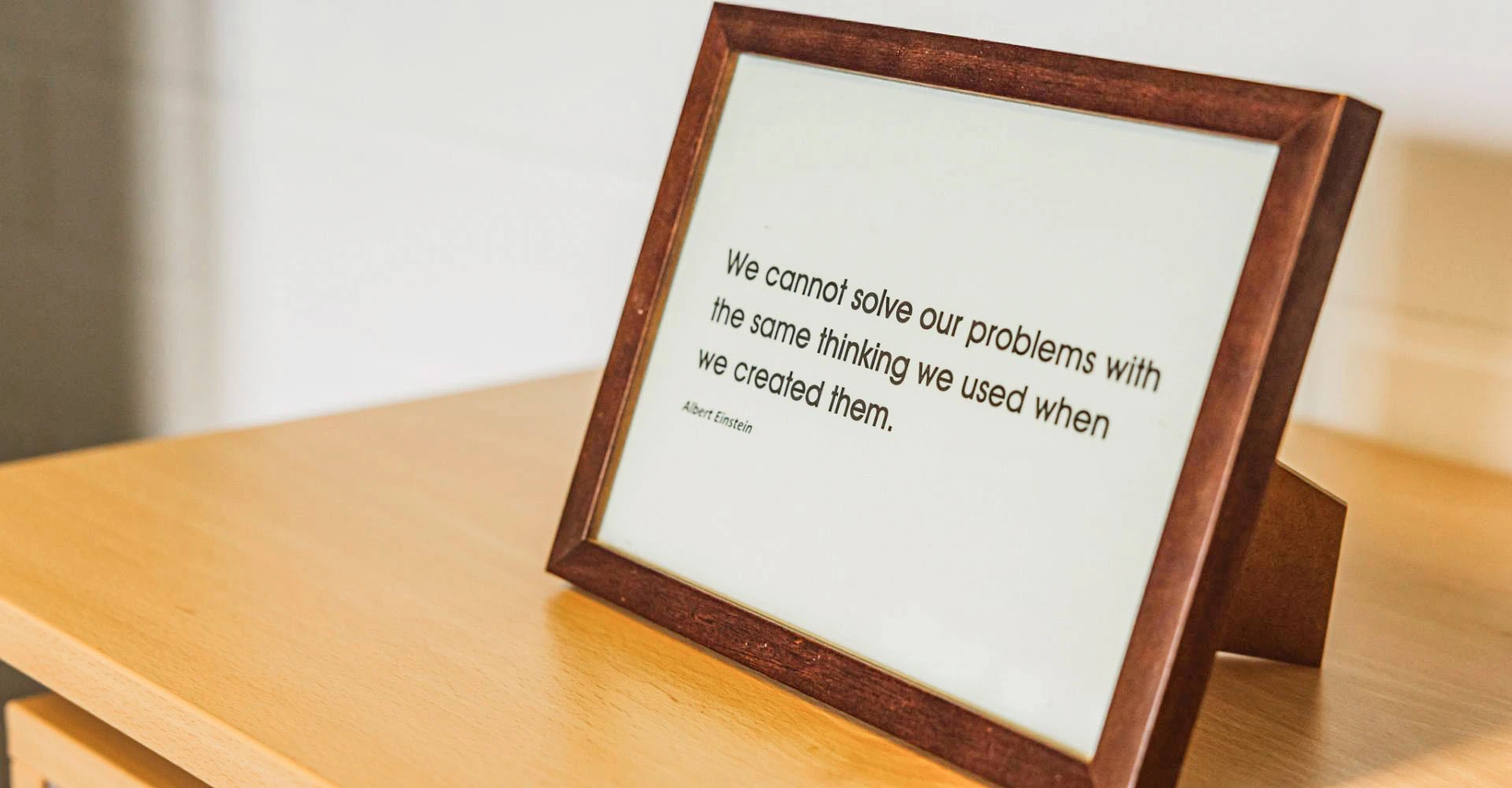 Schlichtes gerahmtes Bild mit dem Schriftzug We cannot solve our problems with the same thinking we used when we created them. Zitat von Albert Einstein.