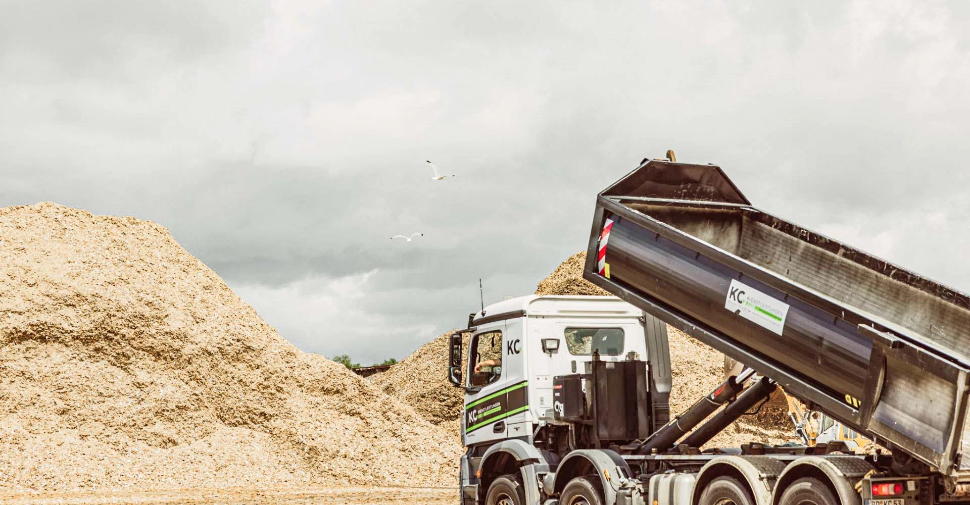 LKW vor einem Haufen Holzspähnen