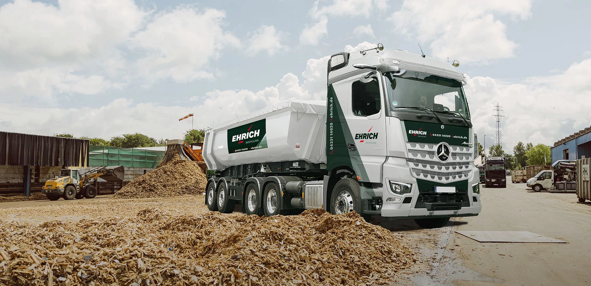 Ein Ehrich LKW neben einem Haufen Holzabfälle auf dem Ehrich Werkhof