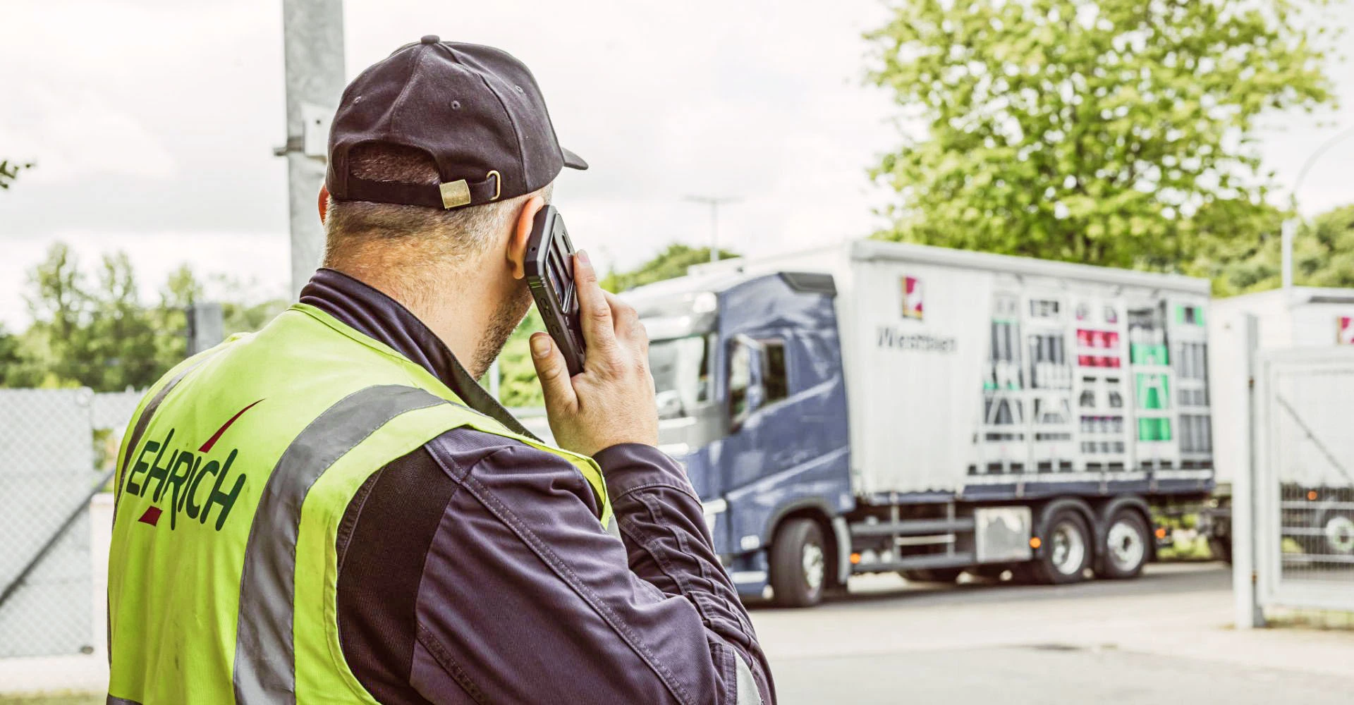 Mitarbeiter steht draußen vor einem LKW und telefoniert